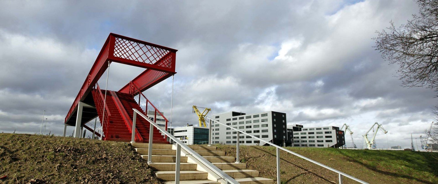 slender, modern, bright red foot and cycle bridge across railway